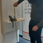 Fotografía de un miembro de Libre Acceso A.C realizando la evaluación de accesibilidad sobre la altura de los cajeros y teléfonos al servicio del usuario