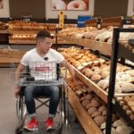 Fotografía de un usuario de silla de ruedas tomando pan de los estantes para la evaluación de accesibilidad en la zona de panadería