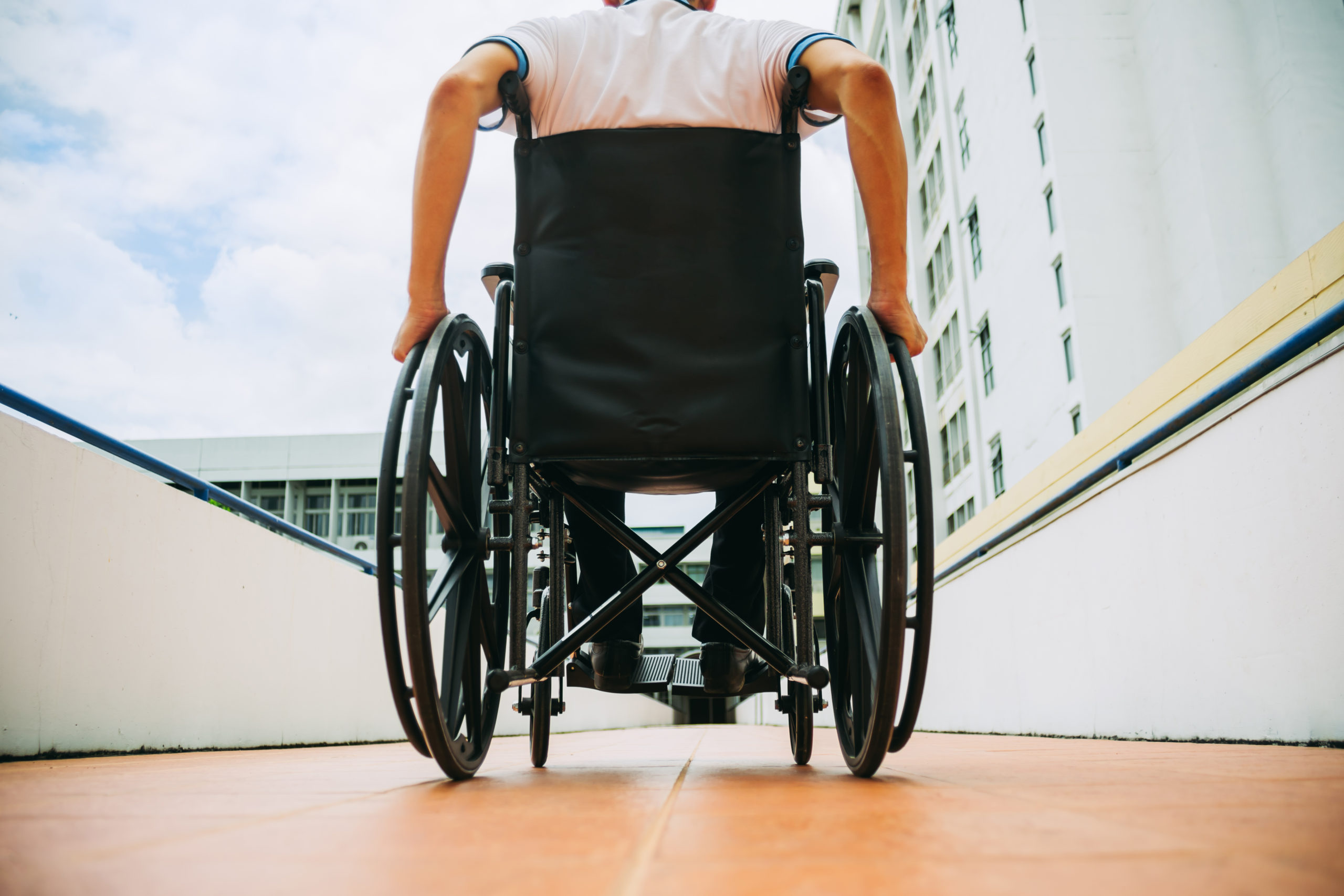 Fotografía de persona usuaria de silla de ruedas en un pasillo de un inmueble.