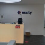 Fotografía de la Recepción Oficinas Essity donde se ve un escritorio y la pared con el logo