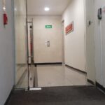 Fotografía de Schneider National Sede México de Puerta de acceso a oficinas la cual es de crital y en la fotografía se puede apreciar el pasillo de entrada