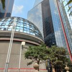 Fotografía Bolsa Mexicana de Valores Fachada en la que se aprecia el edificio con una cúpula llena de cristales, un árbol y un edificio a lado