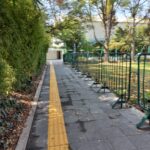Fotografía Circuito Helipuerto donde se puede apreciar el piso podotáctil y varios árboles, arbustos y pasto