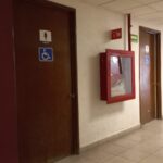 Puerta de acceso a sanitarios con señalización del símbolo internacional de accesibilidad.