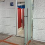 Puerta de cristal con acceso a sanitarios con señalización del símbolo internacional de accesibilidad.