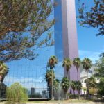 Edificio con pared espejo y un lago artificial de frente