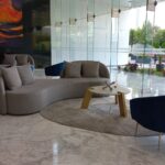 Recepción del inmueble dónde se aprecia una sala con un sillón para cuatro personas, dos sillones individuales y una mesa al centro, con ventanales del lado derecho.