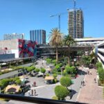 Fotografía panorámica que muestra la explanada de la Universidad con mesas y sombrillas