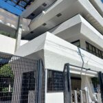 Entrada a la Universidad por la calle Francisco MurguÍa, se aprecia edificio con fachada blanca y entrada por torniquetes o acceso a autos