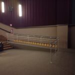 Rampa en una sala de cine adaptada para personas con discapacidad, con una barandilla de seguridad y escalones iluminados para facilitar el acceso.